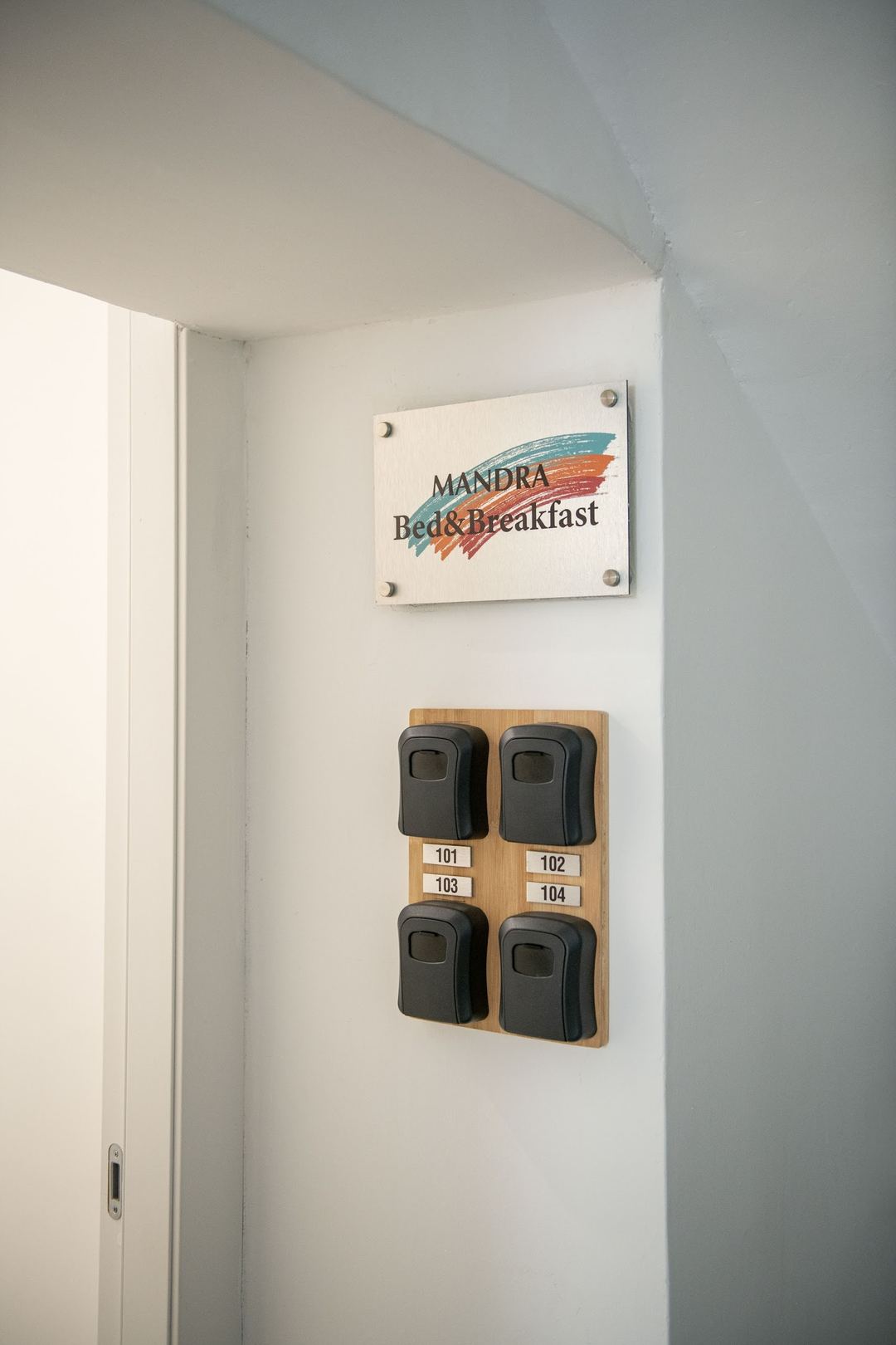 A wall-mounted key holder displaying the Mandra Bed & Breakfast sign above four labeled lockboxes for rooms 101-104.